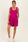woman wearing a fuchsia maternity romper with tie straps and pockets, showcasing her baby bump