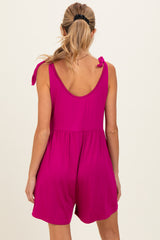 woman wearing a bright pink maternity romper with tie shoulder details, showing back view and relaxed fit