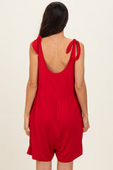 woman wearing a red sleeveless romper with tied shoulder straps, viewed from the back