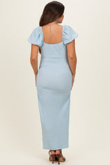 woman wearing a light blue maternity maxi dress with short puff sleeves and a fitted waist, showing a baby bump from the back