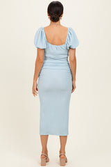 woman wearing a light blue fitted midi dress with puff sleeves and ruching details, viewed from the back