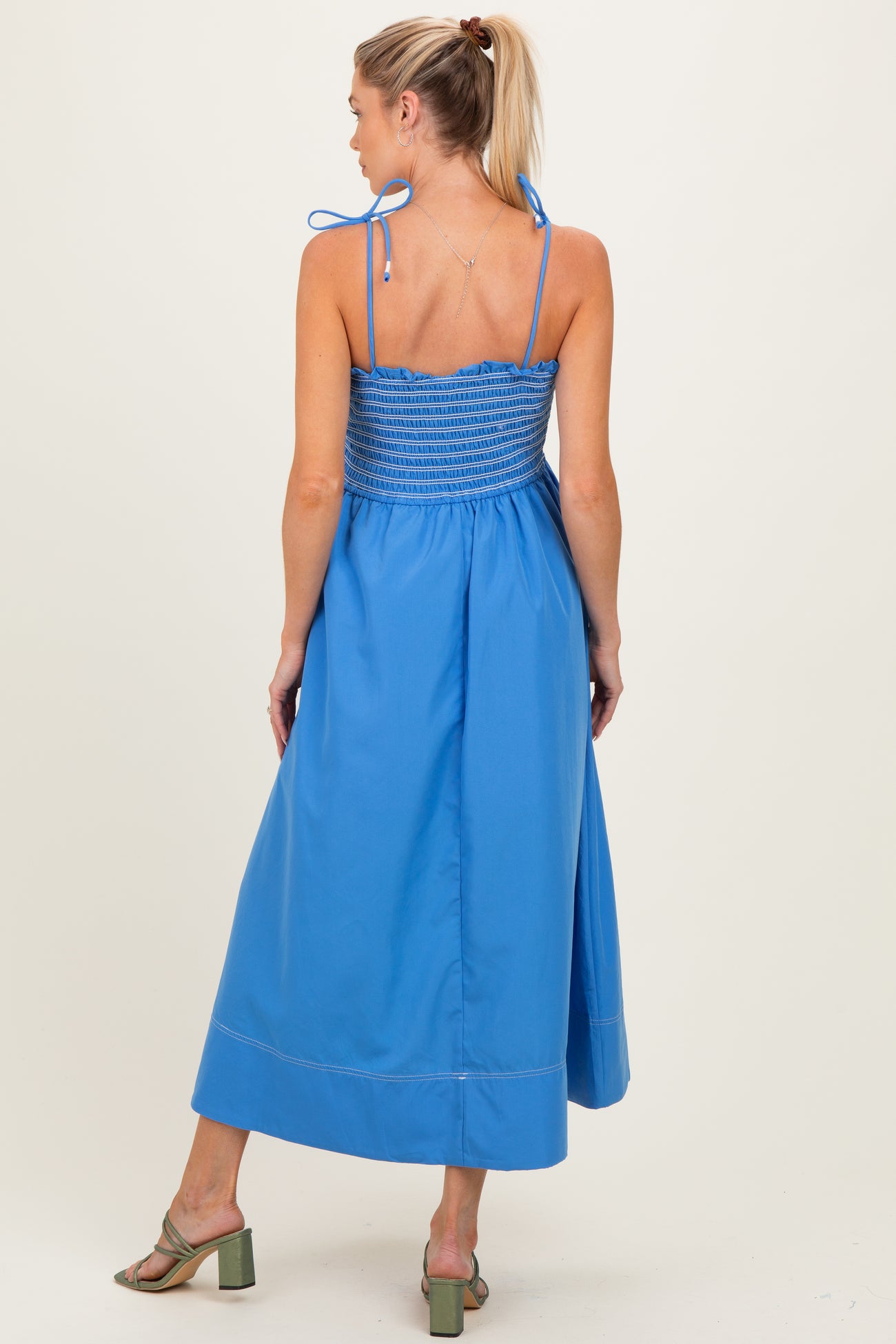 woman wearing a blue maternity maxi dress with adjustable straps and smocked bodice, viewed from the back