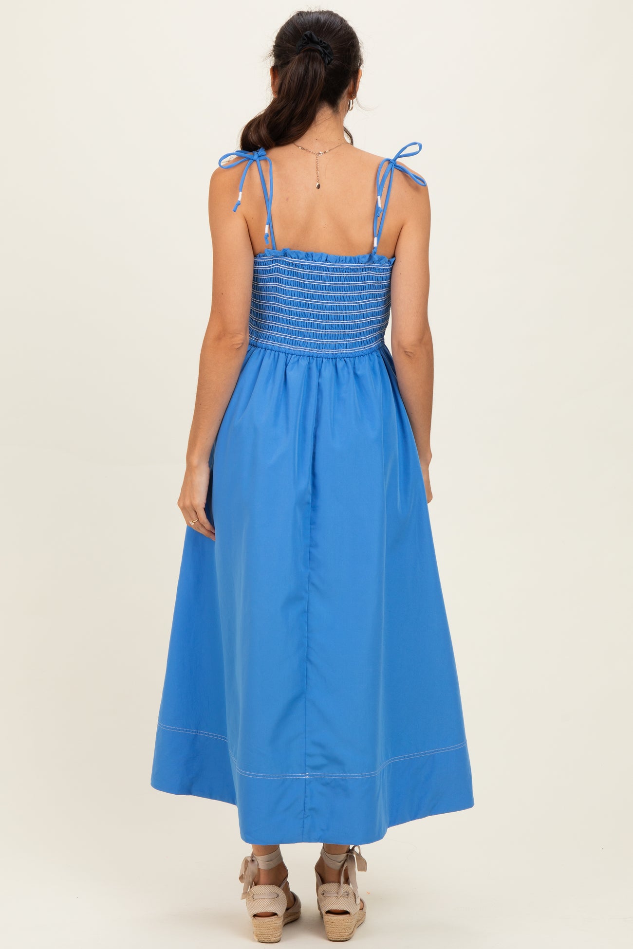 woman wearing a back view of a blue maxi dress with smocked bodice and tie straps