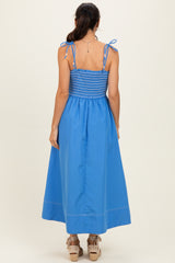 woman wearing a back view of a blue maxi dress with smocked bodice and tie straps