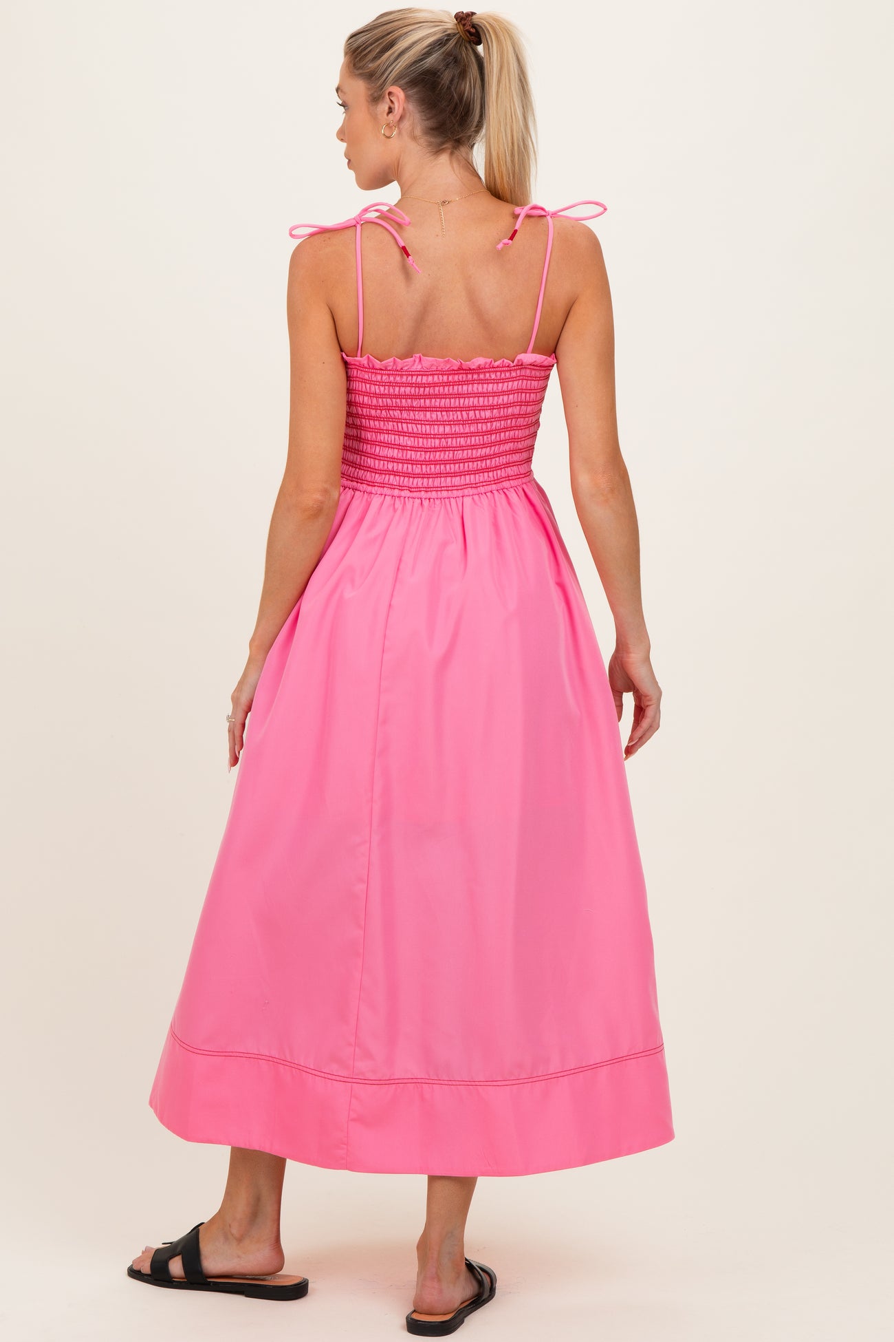 woman wearing a pink maternity maxi dress with smocked bodice and adjustable ties on the straps