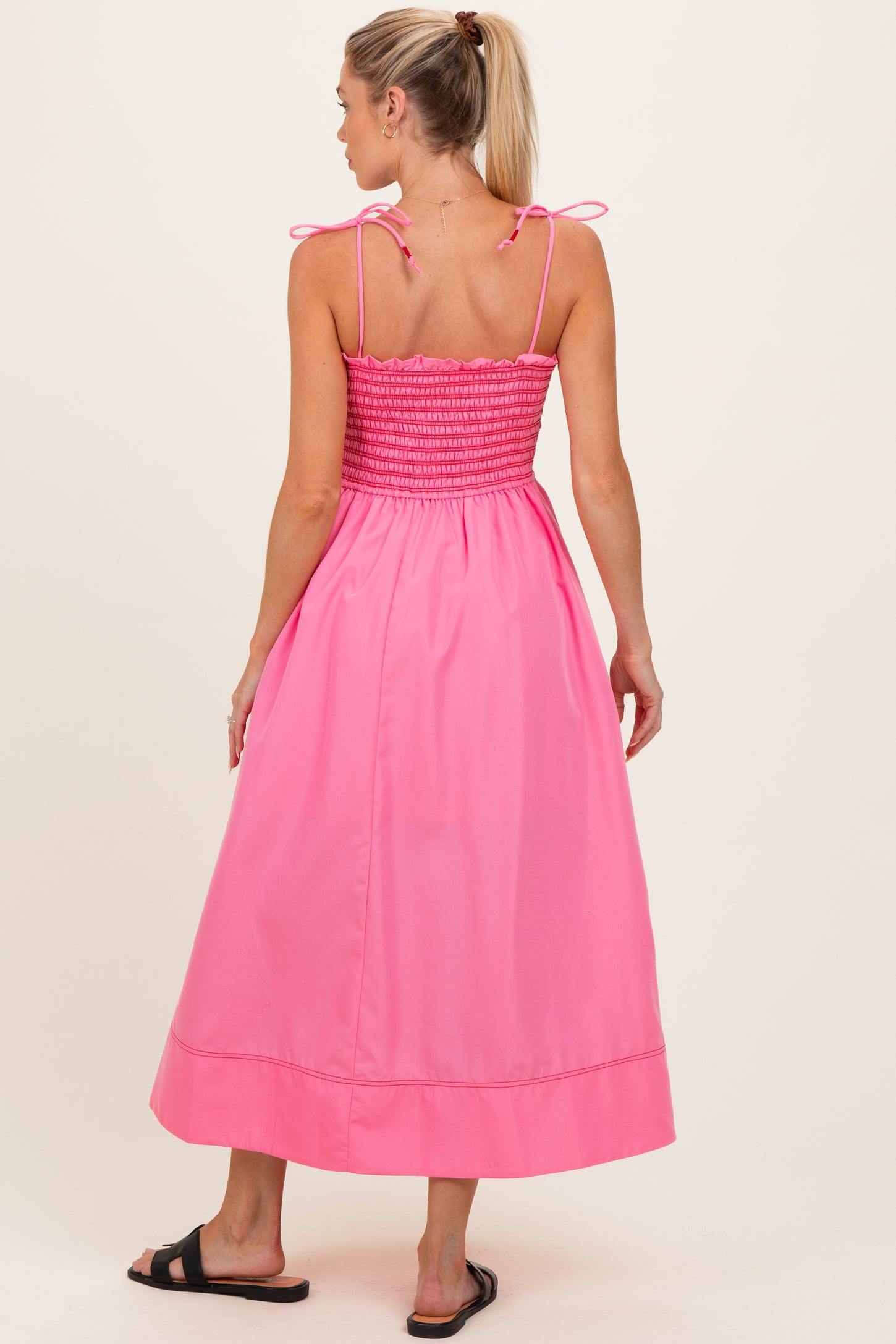 woman wearing a pink maternity maxi dress with smocked bodice and adjustable ties on the straps