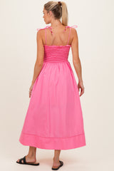 woman wearing a pink maternity maxi dress with smocked bodice and adjustable ties on the straps