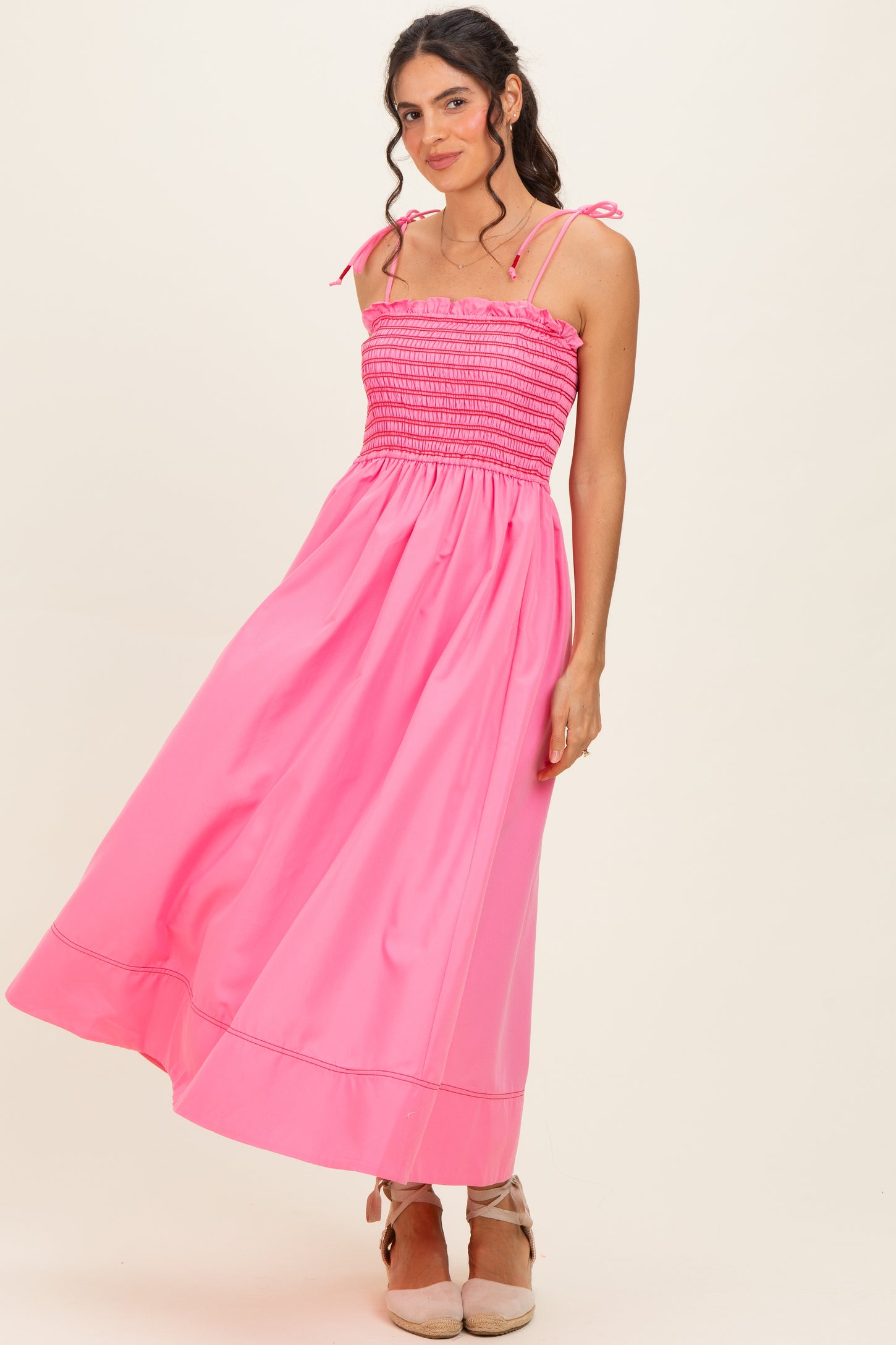 woman wearing a bright pink off-the-shoulder maxi dress with smocked bodice and tie straps