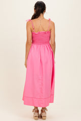 woman wearing a bright pink backless maxi dress with smocking detail and adjustable straps