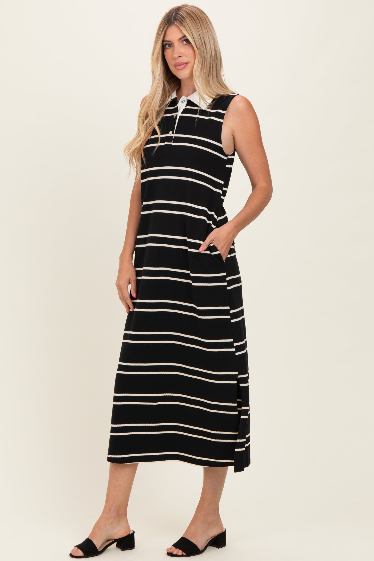 woman wearing a black and white striped sleeveless maxi dress with a collar and side pockets