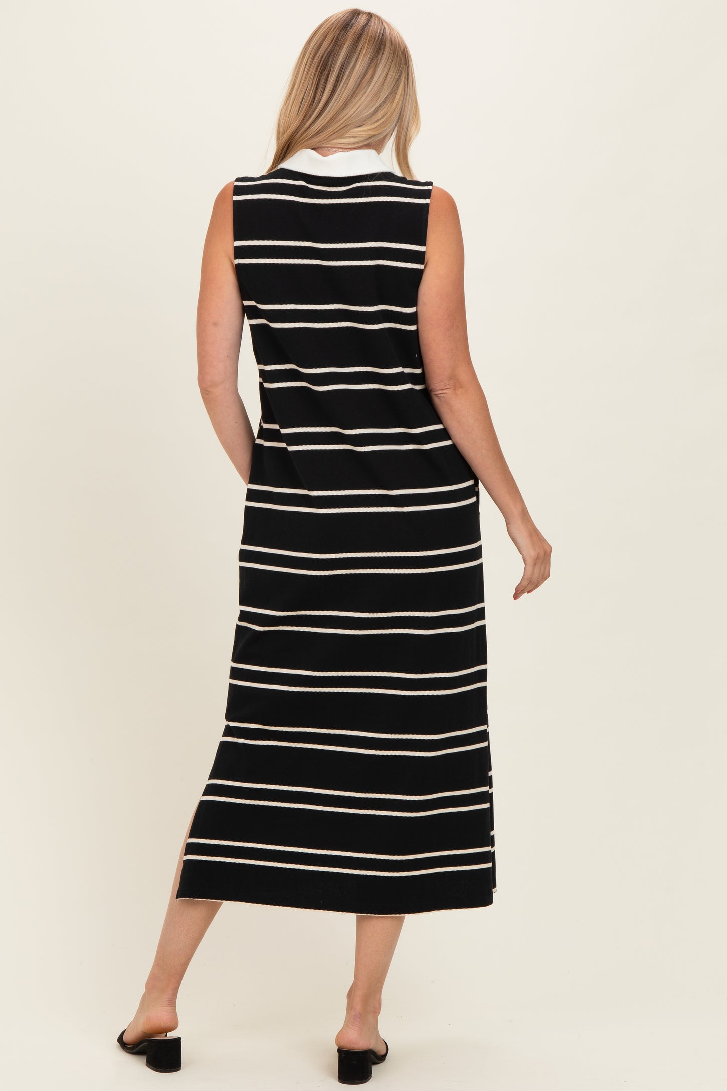 woman wearing a black and white striped sleeveless maxi dress, view from the back