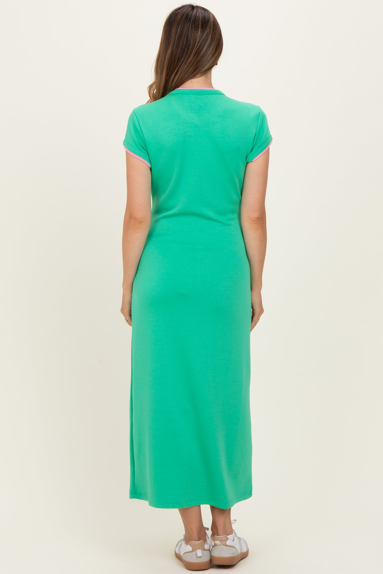 woman wearing a green maternity maxi dress with short sleeves, visible baby bump from the back