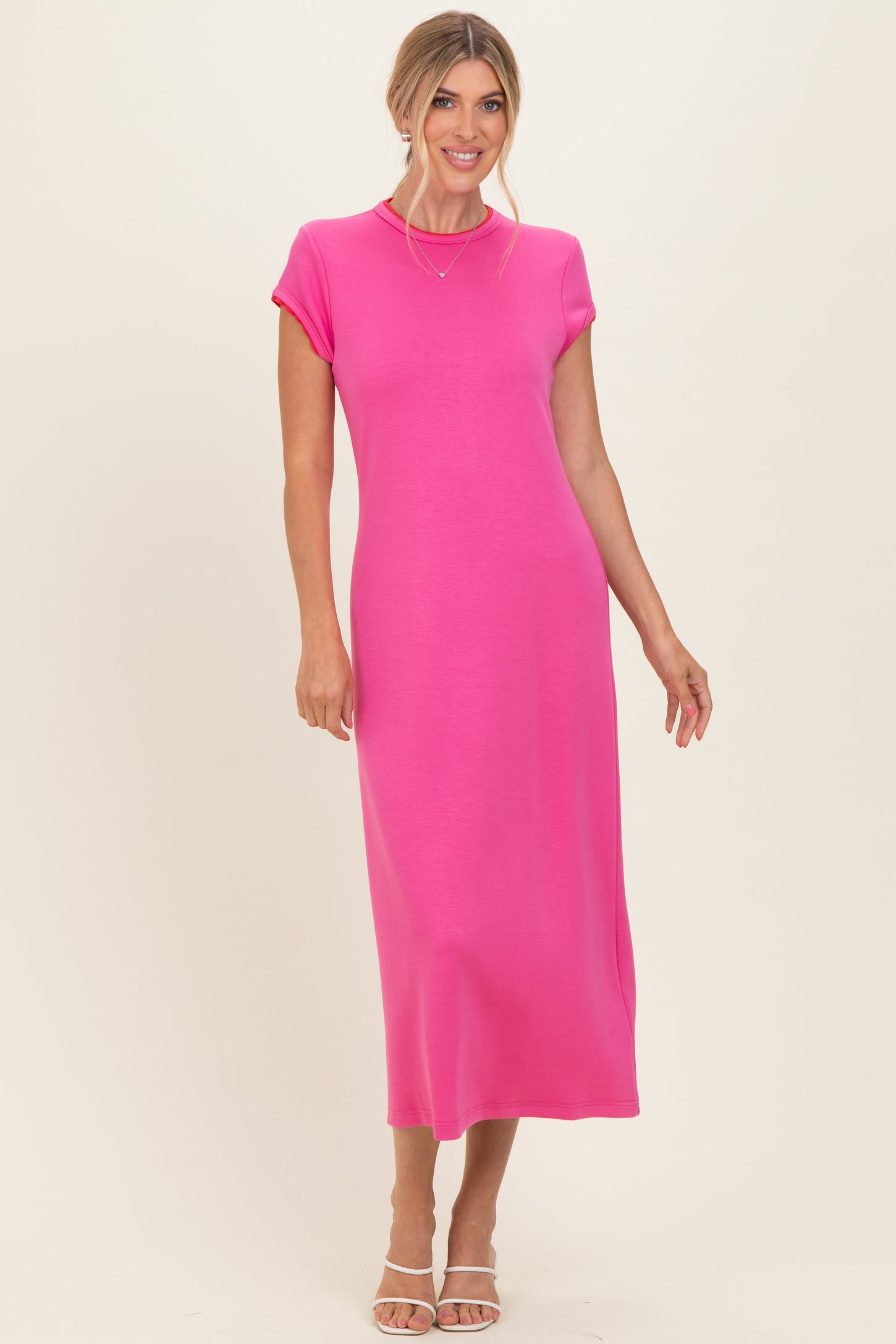 woman wearing a bright pink short sleeve maxi dress standing against a neutral background