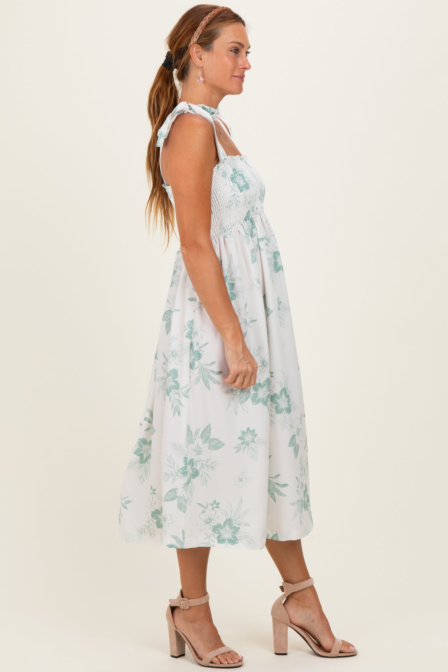 woman wearing a white floral sundress with smocked bodice and tie straps, paired with strappy nude heels