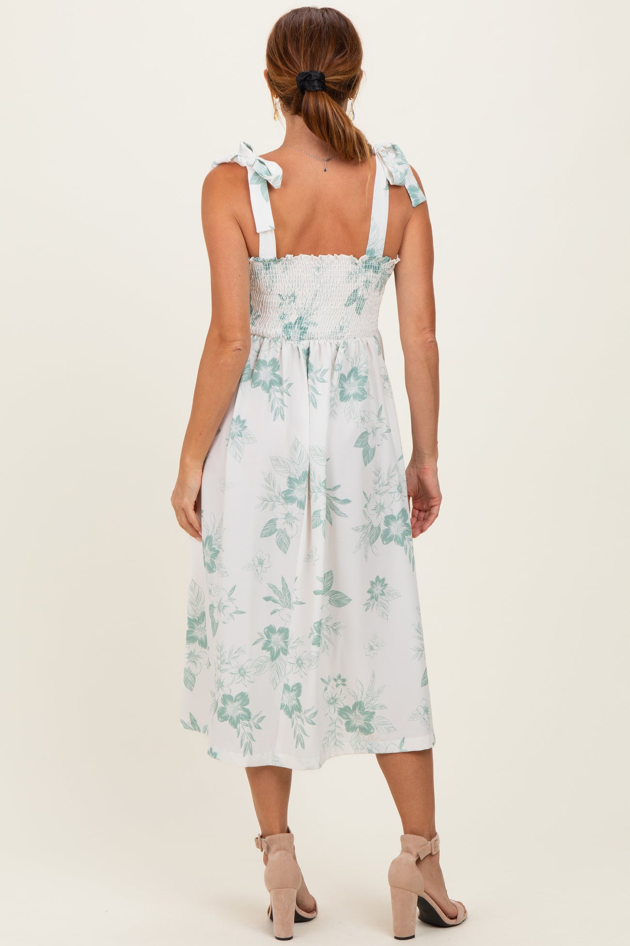 woman wearing a white floral midi dress with smocked bodice and tie shoulder straps, viewed from the back