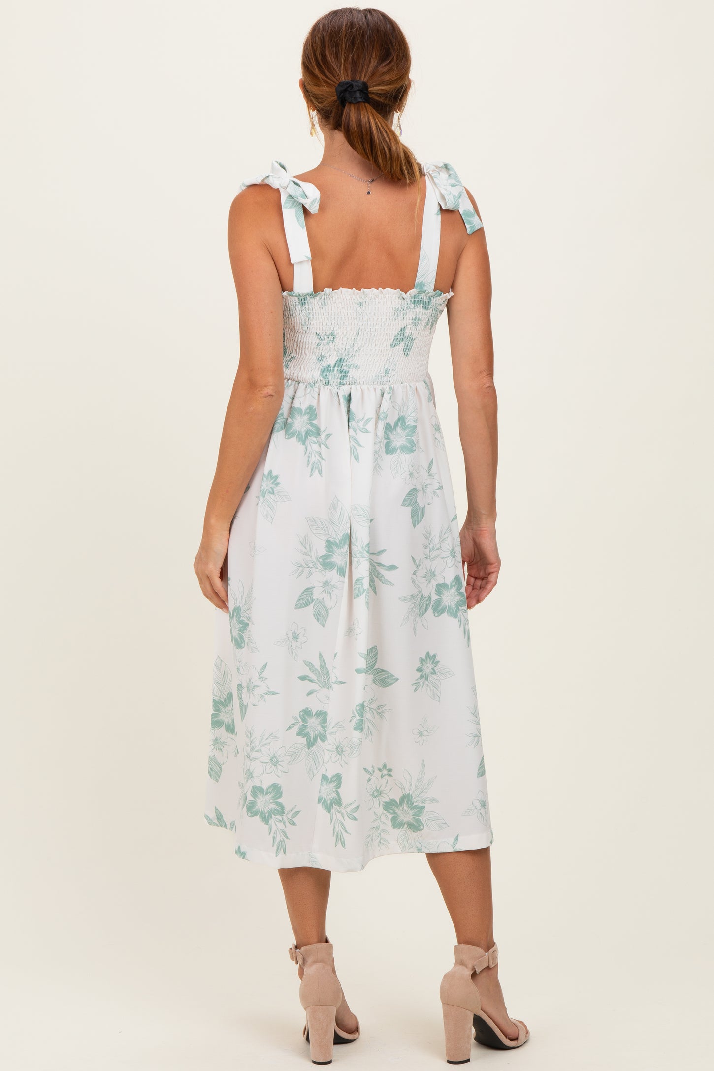 woman wearing a white floral midi dress with smocked bodice and tie shoulder straps, viewed from the back