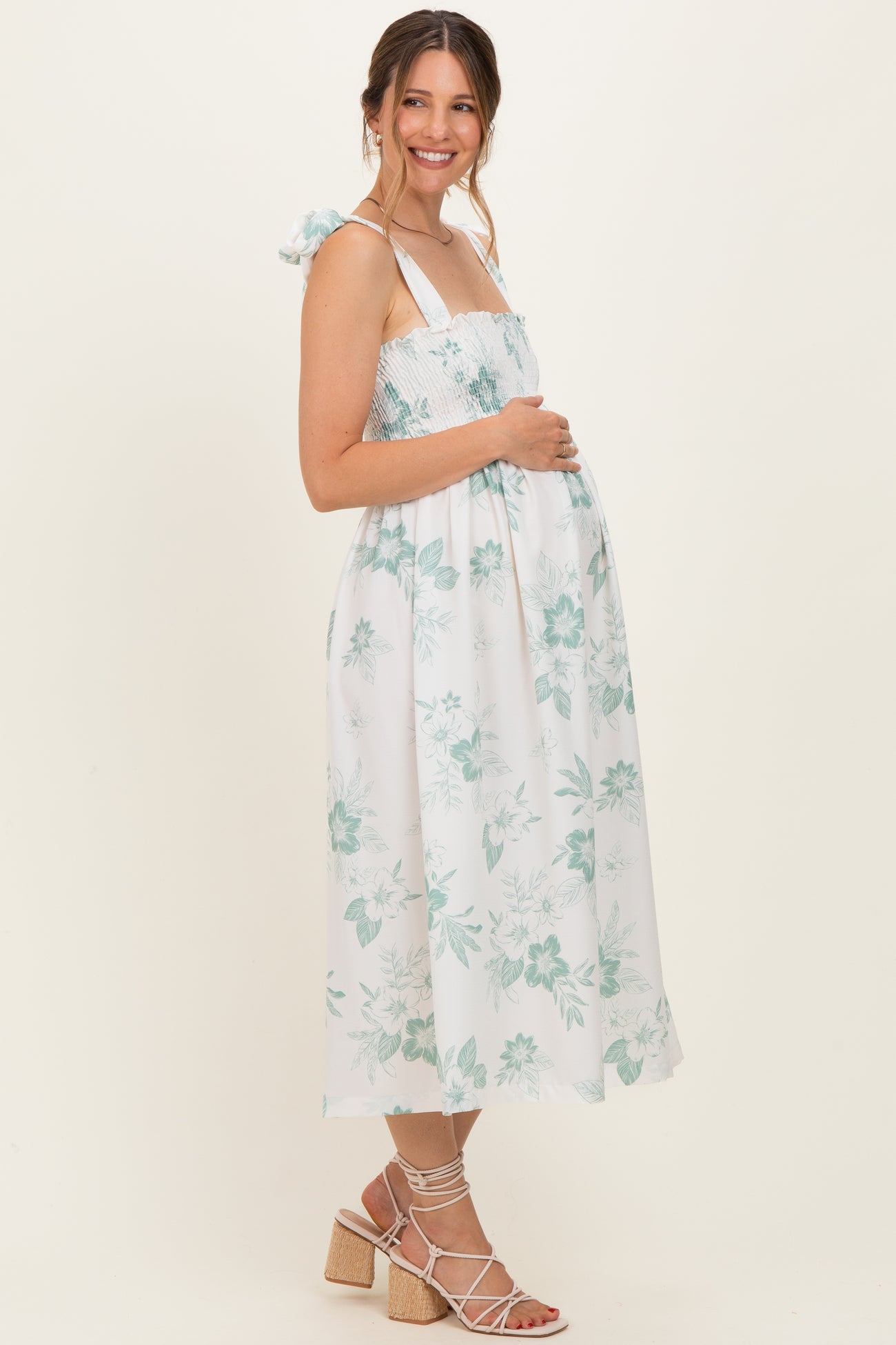 woman wearing a white floral maternity dress with adjustable straps and a visible baby bump