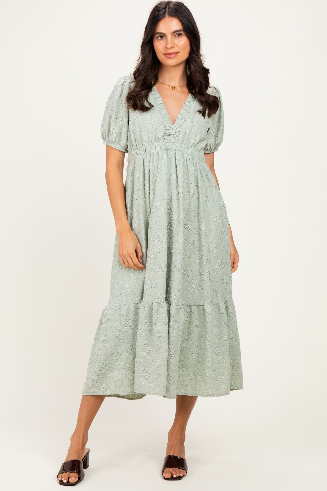 woman wearing a light green puff sleeve midi dress with a v-neck and tiered skirt, standing against a neutral background