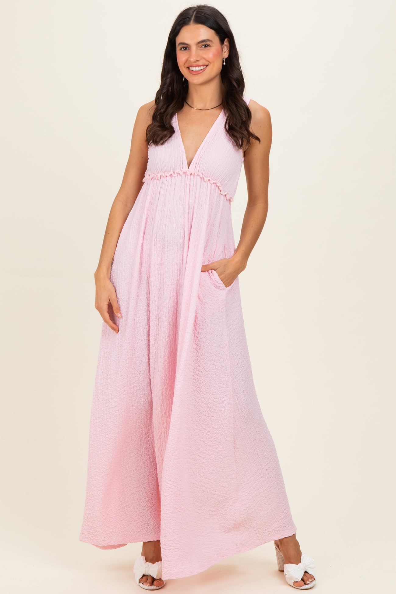 woman wearing a light pink sleeveless maxi dress with a v-neckline and pockets