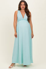 woman wearing a light blue sleeveless maternity maxi dress with a deep v-neck and empire waist, showcasing her baby bump