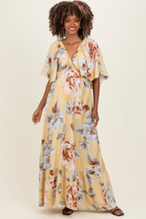 woman wearing a yellow floral maternity maxi dress with short sleeves and a V-neckline, showcasing her baby bump