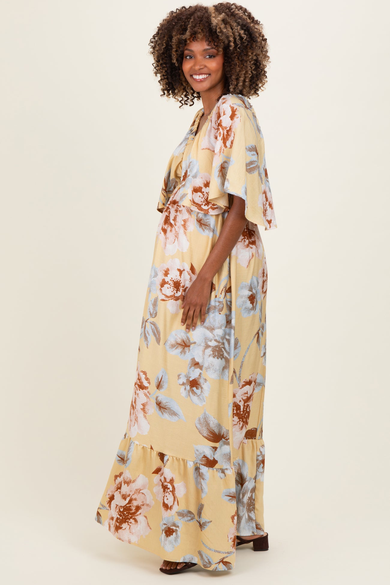 woman wearing a floral yellow maxi dress with flutter sleeves and a visible baby bump