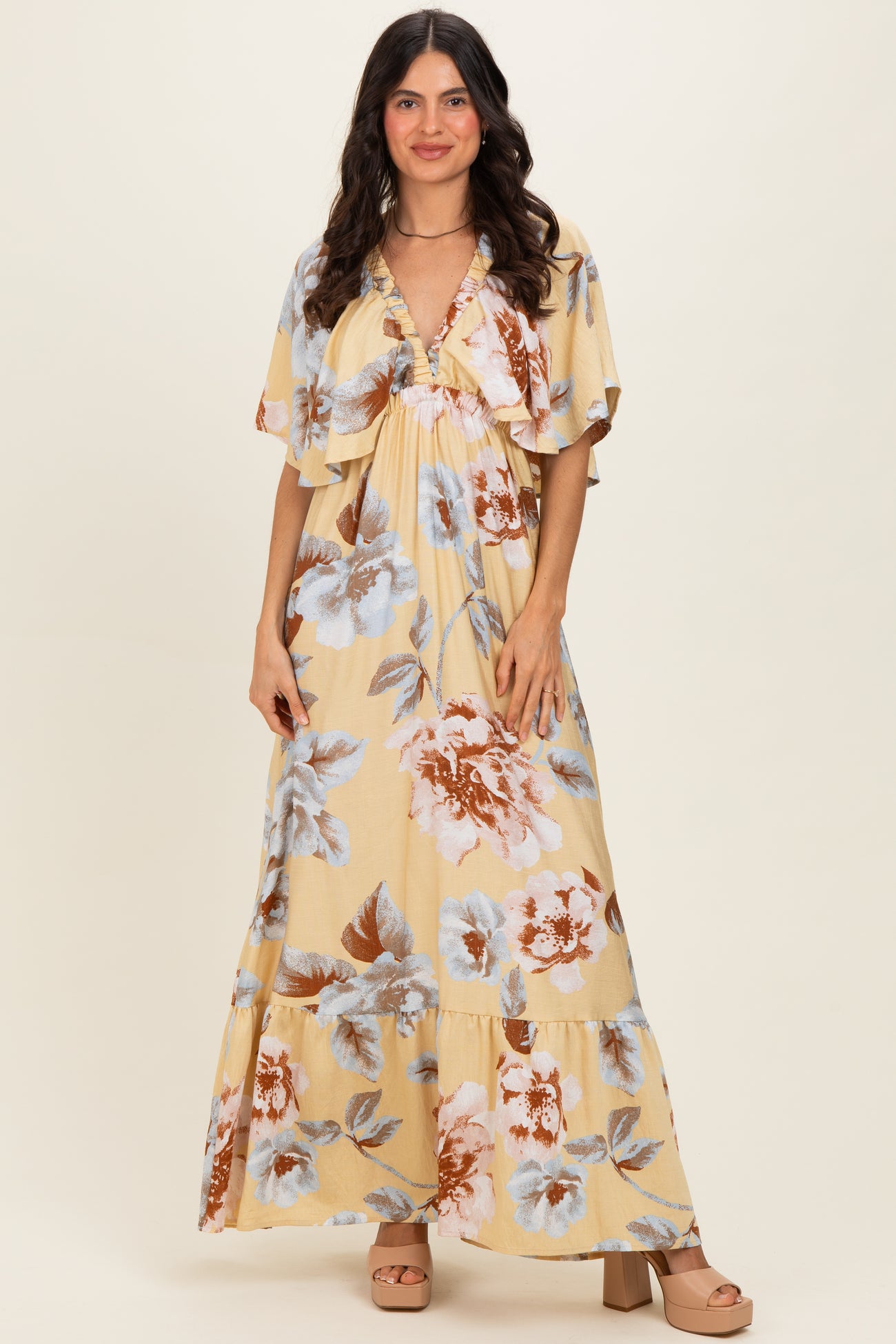 woman wearing a yellow floral maxi dress with flutter sleeves and a tiered skirt