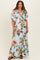 woman wearing a light blue floral maternity maxi dress with a deep v-neck and flutter sleeves, showing her baby bump