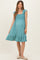 woman wearing a teal maternity dress with ruffle sleeves and a smocked bodice, showcasing her baby bump