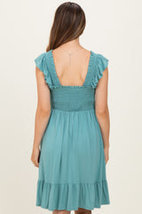 woman wearing a teal maternity dress with ruffled sleeves and a smocked back, showcasing a flowing skirt