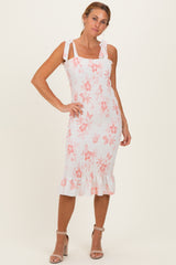 woman wearing a white floral midi dress with smocked bodice and ruffled hem, tied straps, posing confidently