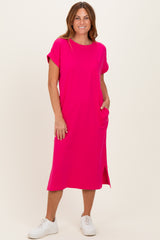 woman wearing a bright pink short sleeve midi dress with pockets and side slits, styled with white sneakers