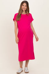 woman wearing a bright pink maternity dress with short sleeves and a pocket, smiling and showing her baby bump