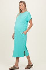 woman wearing a turquoise maternity dress with a pocket and side slits, showing her baby bump