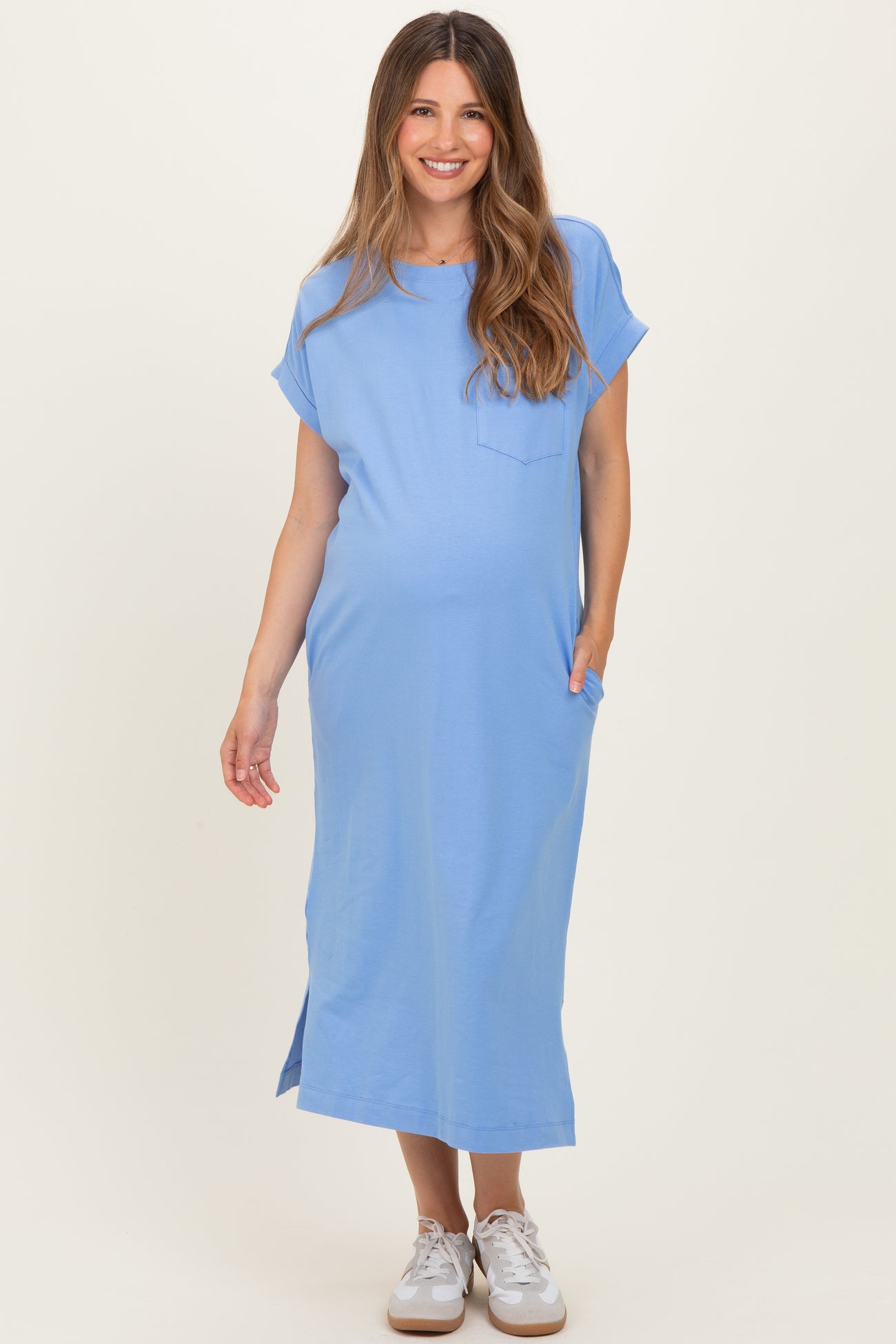 woman wearing a light blue maternity dress with short sleeves and pockets, displaying her baby bump