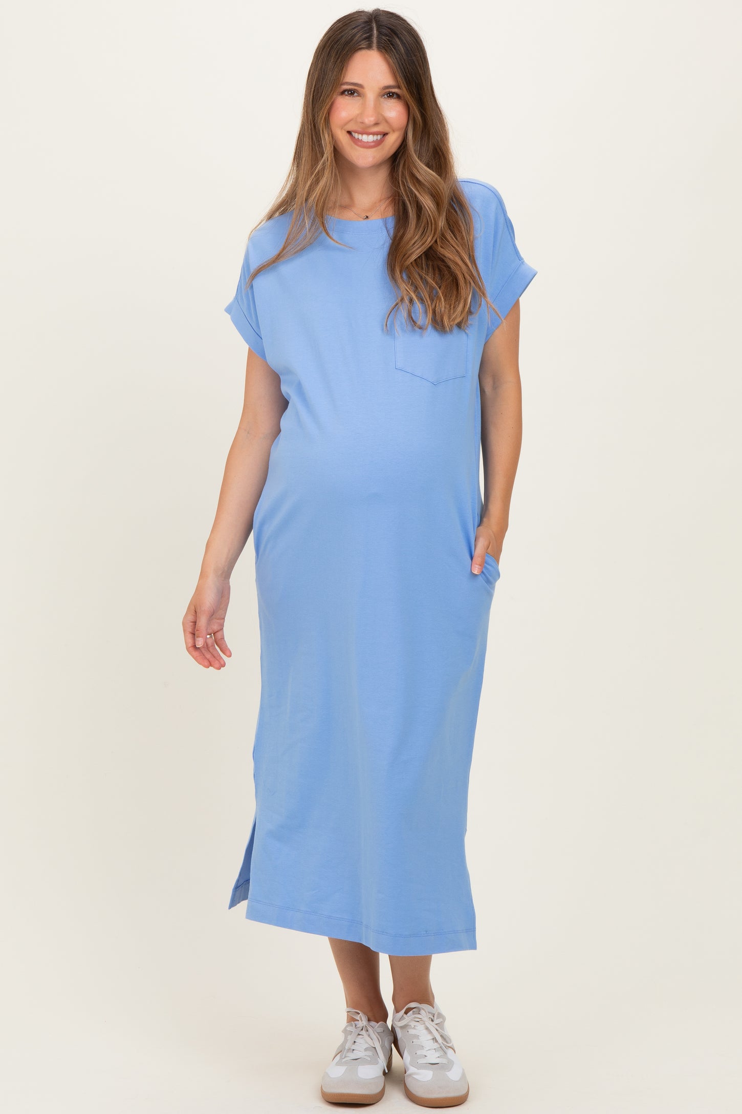 woman wearing a light blue maternity dress with short sleeves and pockets, displaying her baby bump