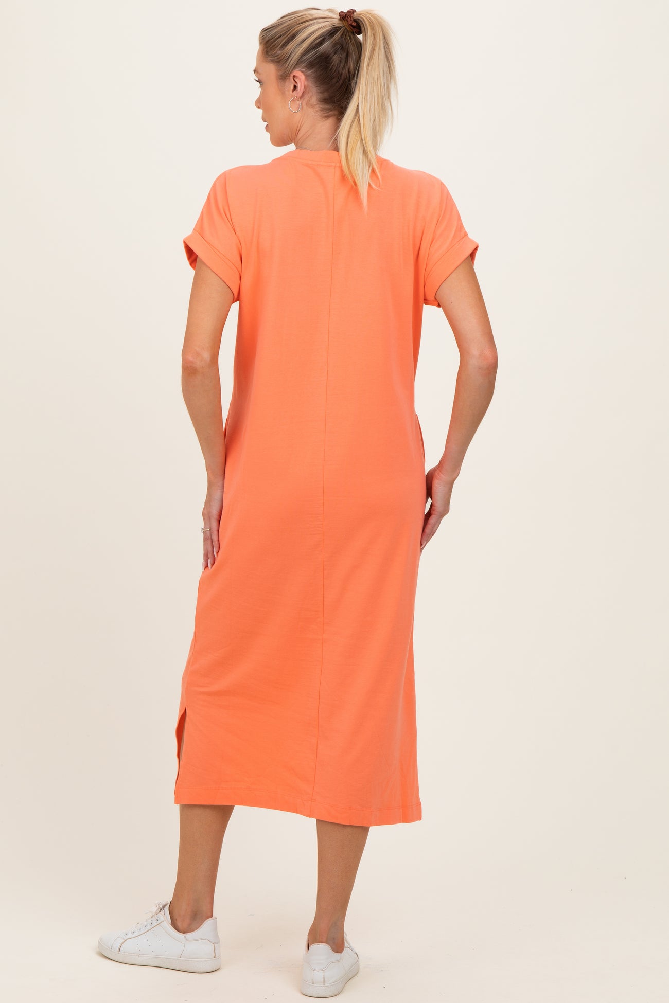 woman wearing an orange maternity dress with short sleeves and side slits, shown from the back