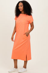woman wearing a bright orange short sleeve pocket dress with side slits and white sneakers