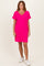 woman wearing a bright pink short sleeve v-neck dress with rolled sleeves and white sneakers