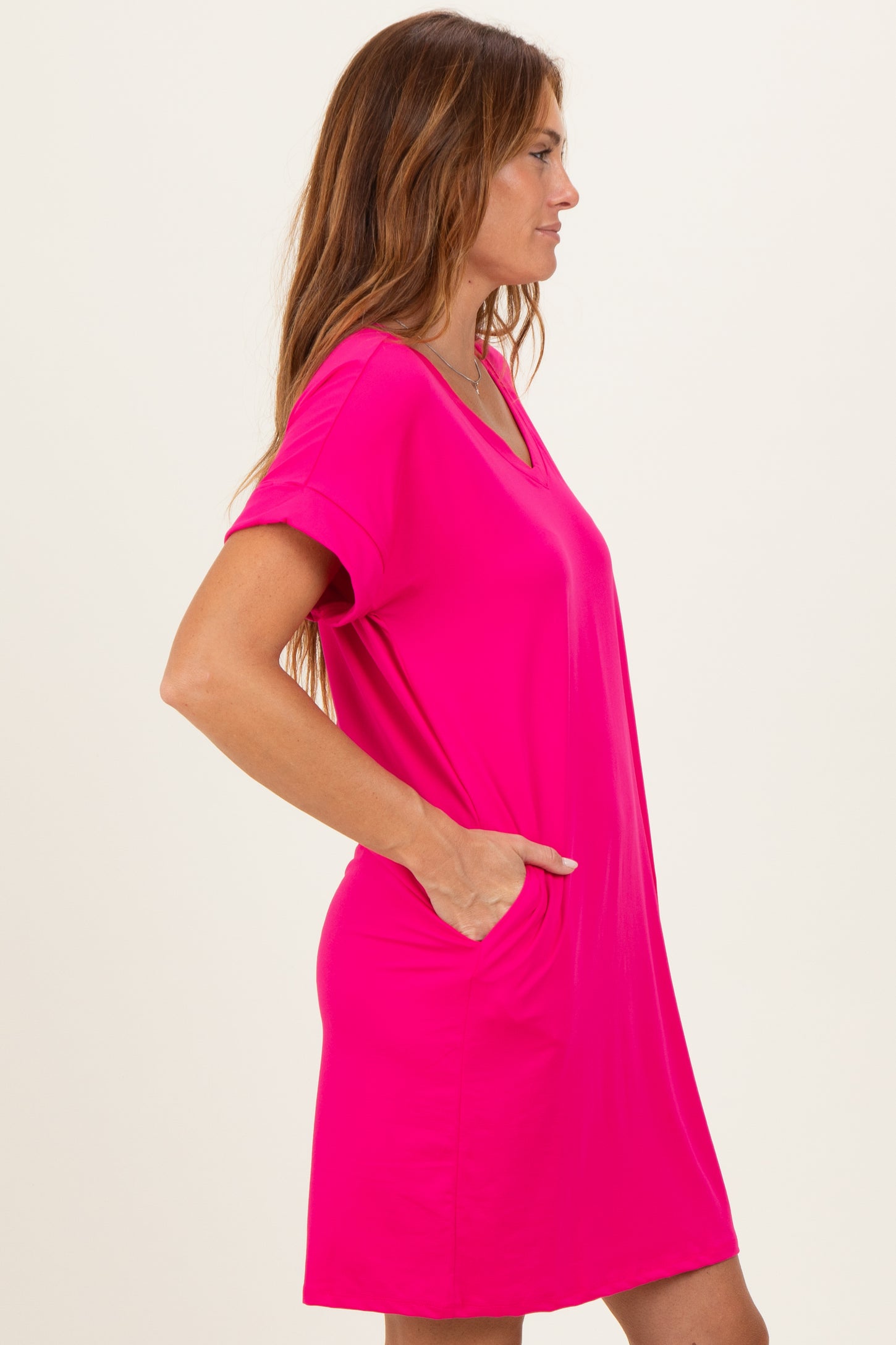 woman wearing a bright pink short sleeve casual dress with a v-neck and pockets