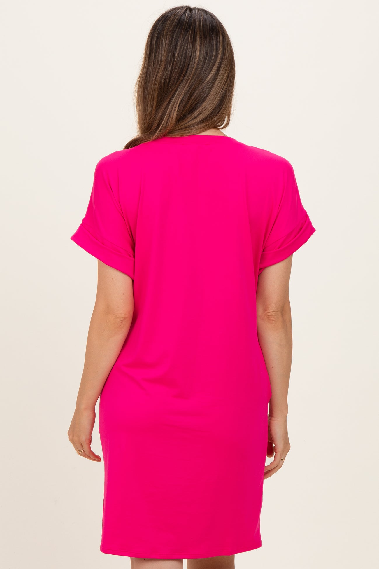 woman wearing a bright pink maternity dress with short sleeves, shown from the back