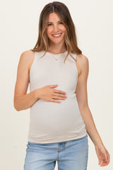 woman wearing a beige maternity tank top and holding her baby bump