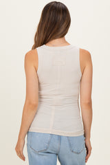 woman wearing a light beige sleeveless maternity top, showing the back view with a slim fit design