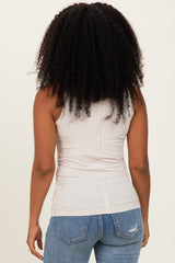 woman wearing a beige fitted tank top with a button detail at the back and blue distressed jeans
