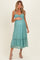 woman wearing a teal lace maternity dress with ruffled neckline and a flared hem, holding her baby bump