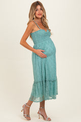 woman wearing a teal lace maternity dress with spaghetti straps and holding her baby bump