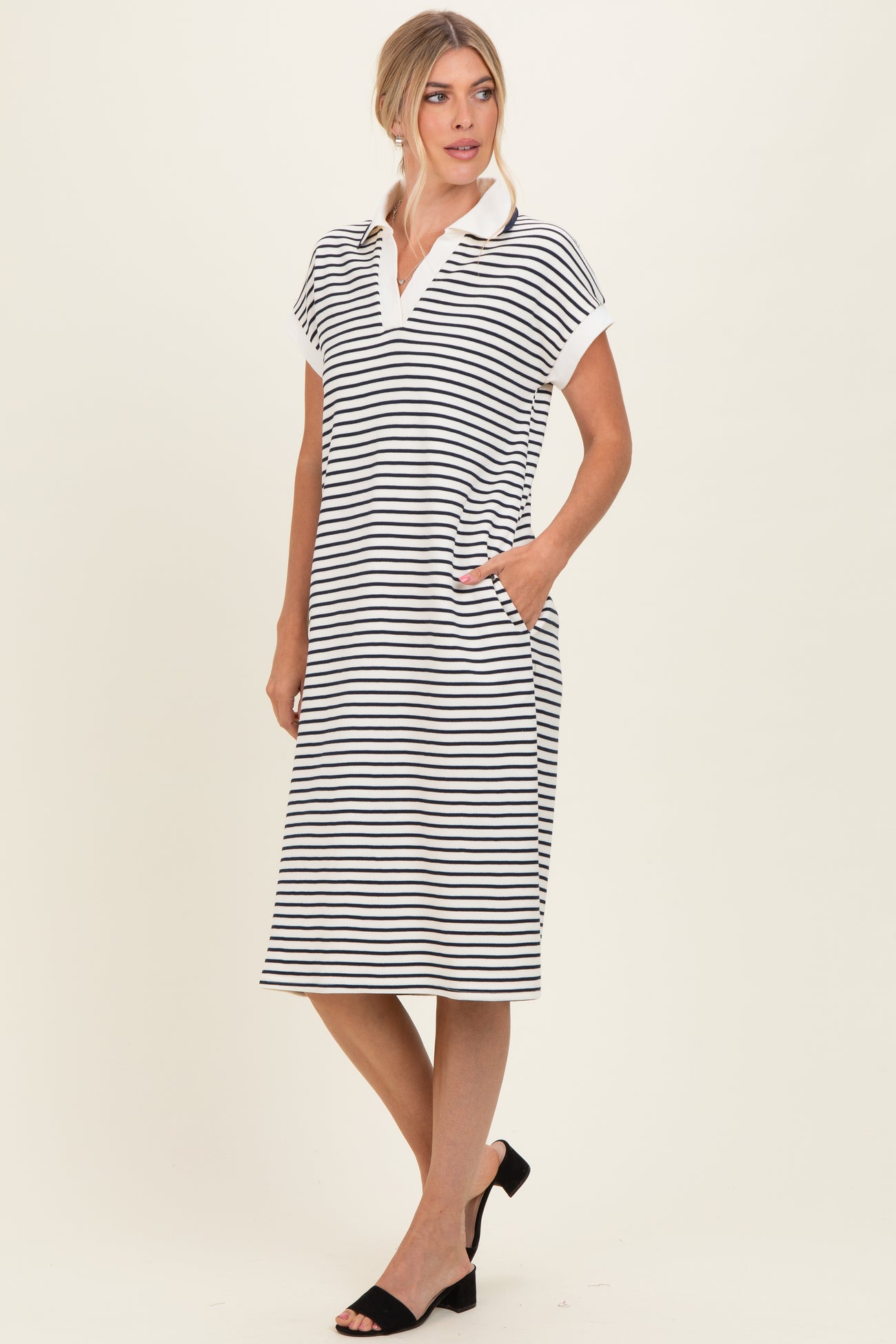woman wearing a black and white striped polo dress with short sleeves and pockets