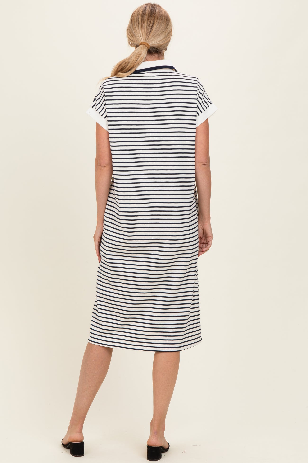 woman wearing a navy and white striped short sleeve dress, view of the back