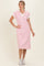 woman wearing a pink and white striped polo midi dress with short sleeves and a collar, styled with white sneakers
