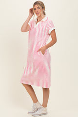 woman wearing a pink and white striped polo dress with short sleeves and pockets, standing in a relaxed pose